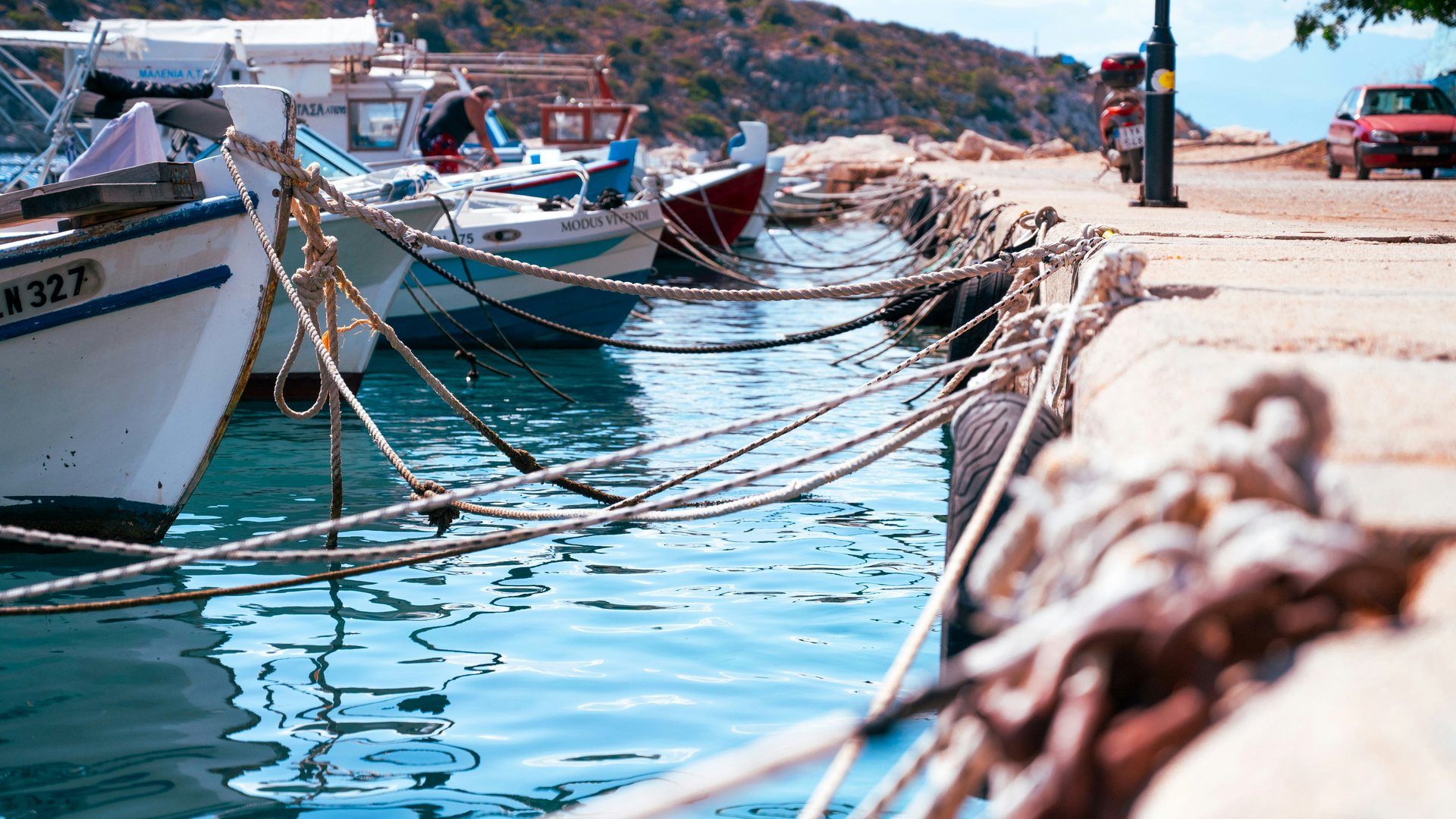 Barques de pêche, cordages et eau turquoise le long d’un quai méditerranéen